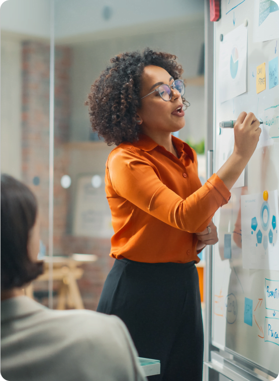 Mulher fazendo uma apresentação sobre consultoria em TI, anotando pontos-chave em um quadro branco.