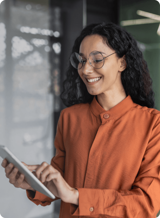 Mulher sorridente com óculos e camisa laranja, usando um tablet no escritório da innolevels.