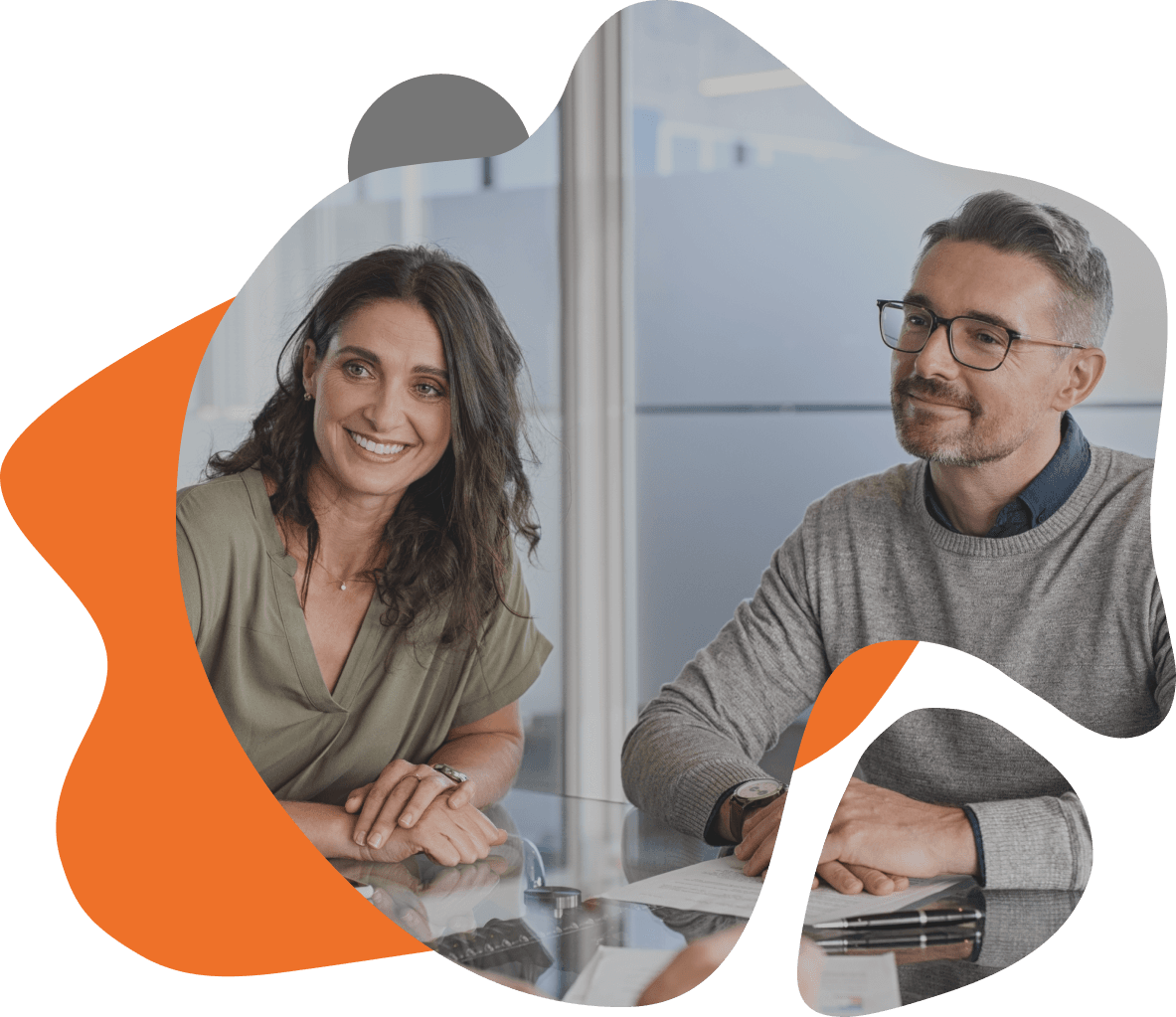 Homem e mulher sentados à mesa, participando de uma reunião sobre consultoria em TI.